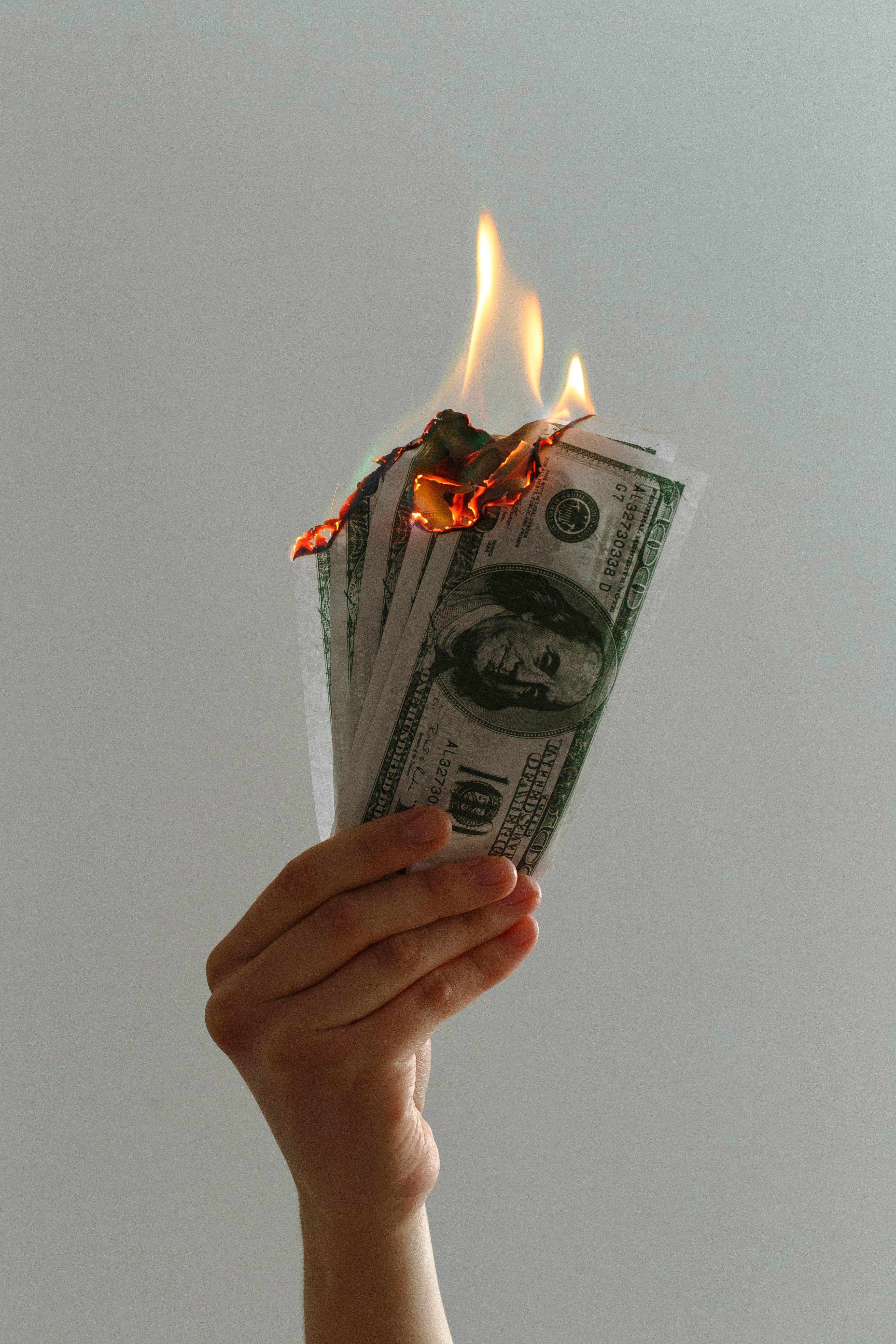 Hand holding burning dollar bills